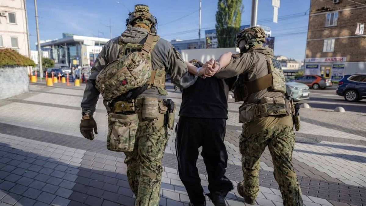 СБУ затримала в Києві 18-річного одесита, якого підозрюють у підготовці теракту Двоє співробітників СБУ у спорядженні ведуть затриманого в наручниках тротуаром у Києві після затримання підозрюваного в держзраді