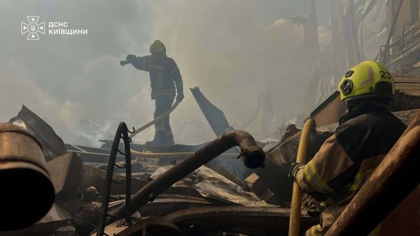 Двоє рятувальників ДСНС гасять осередки пожежі серед завалів зруйнованої конструкції на Київщині