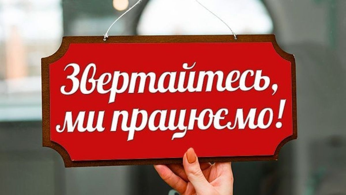 Рука тримає табличку із надписом "Звертайтесь, ми працюємо"