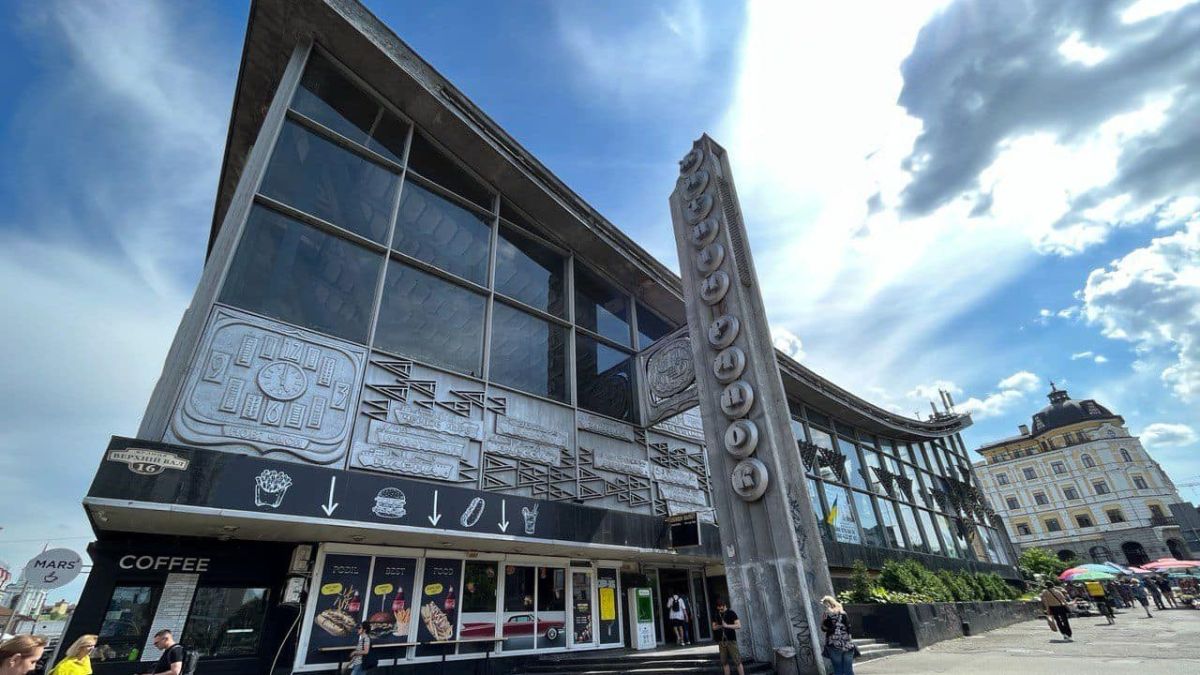 Сучасна будівля з великими вікнами та декоративними панелями радянського періоду на фасаді