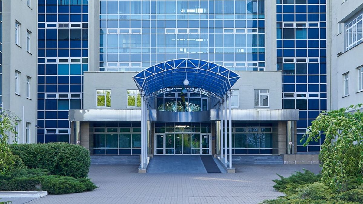 Сучасна будівля з великими скляними вікнами та синім навісом над входом