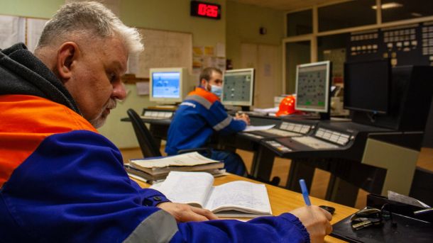 Двоє працівників у синьо-помаранчевій формі в диспетчерській