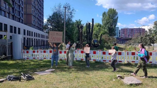 Мешканці з плакатом «Це місце злочину» протестують проти вирубки дерев на Теремках біля огородженої будівельної ділянки