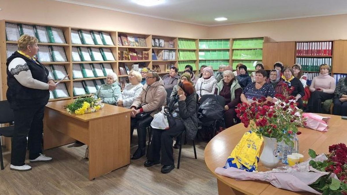 Літні люди сидять за партами в класі, перед ними викладач, вчитель, в класі 15 людей