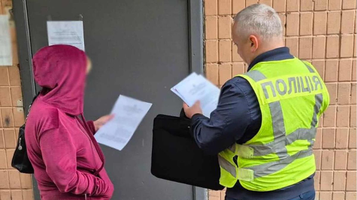 Поліцейський у світловідбивному жилеті вручає жінці документи