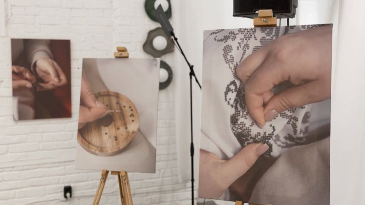 Експозиція виставки «(Не) видимі жінки» — фотографії жіночих рук за рукоділлям на мольбертах у виставковому просторі