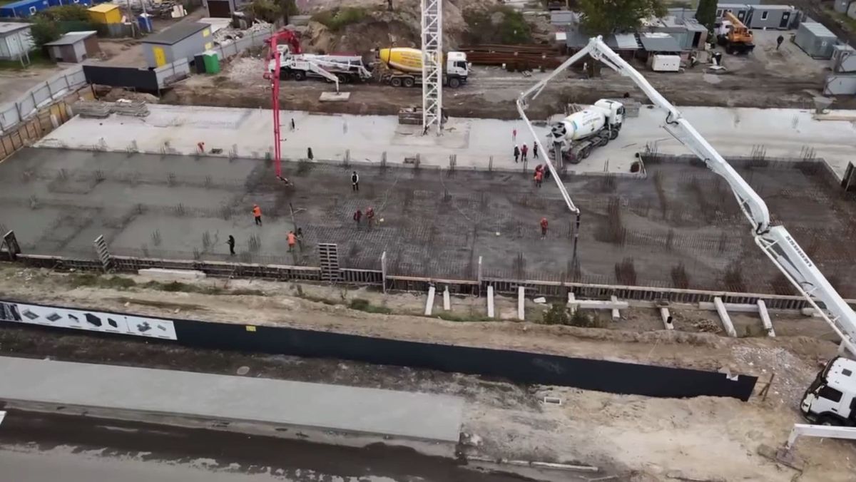 Будівельний майданчик, де робітники заливають бетонну основу великої споруди