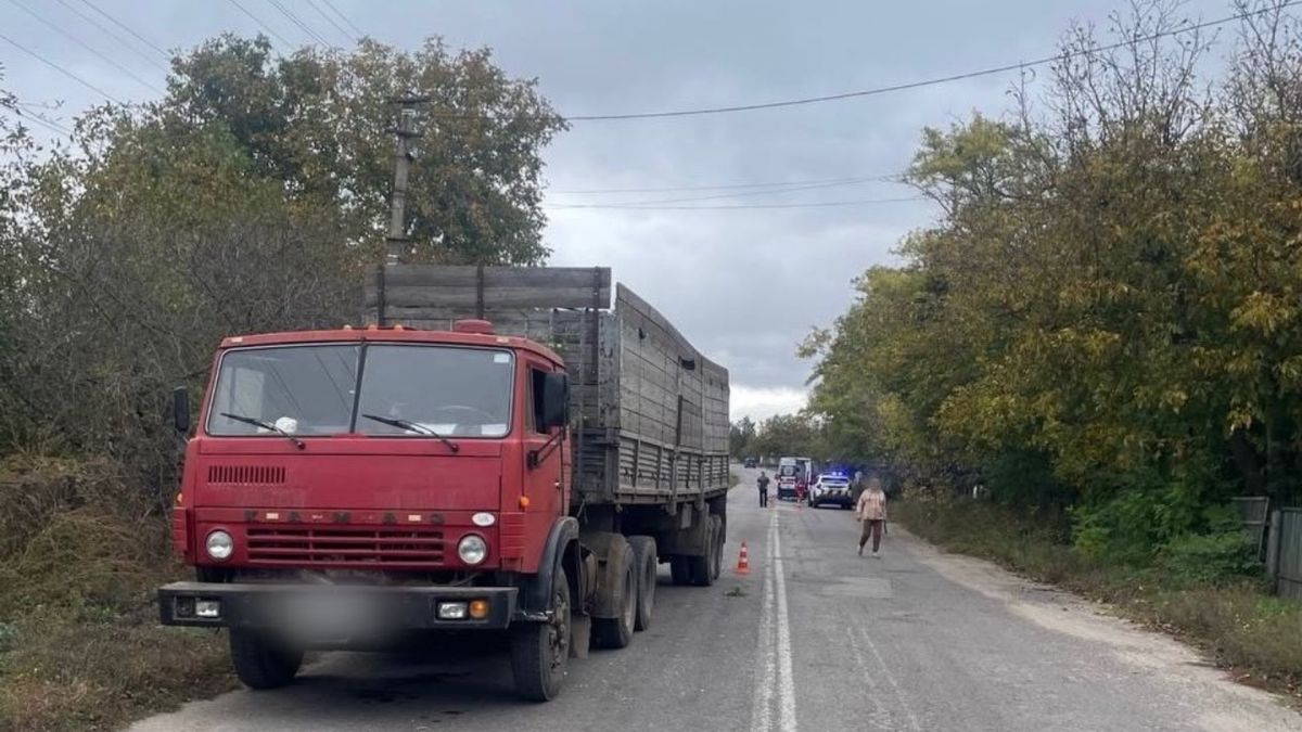 Червона вантажівка Камаз на узбіччі сільської дороги, позаду поліцейське авто і швидка на місці ДТП у Городищі-Пустоварівському