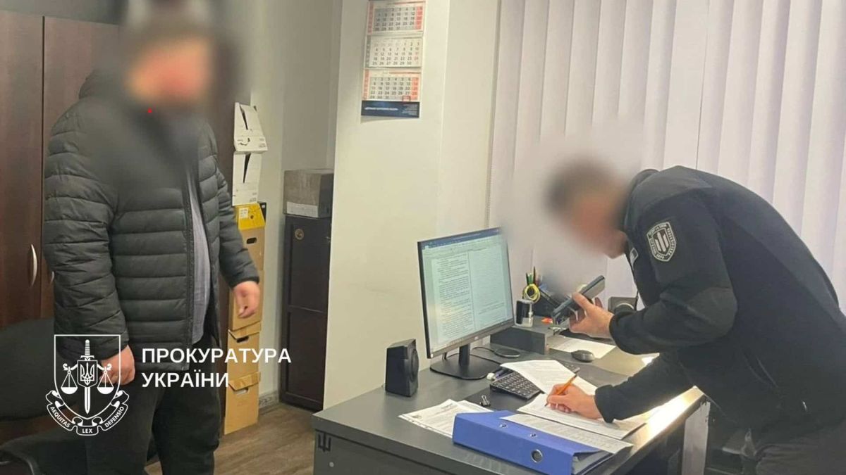 Працівник прокуратури стоїть у поліцейському відділку разом із підозрюваним, обидва чоловіки із заблюреними обличчями