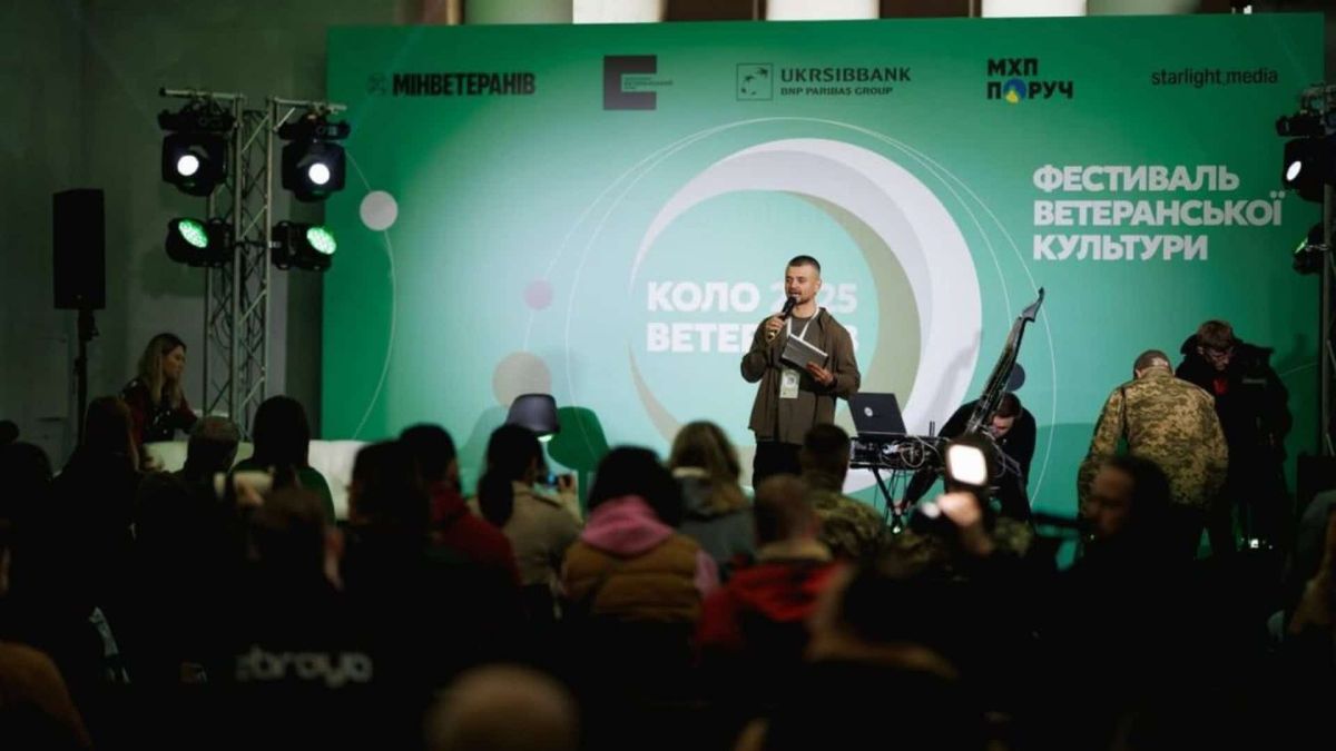 Виступ на сцені фестивалю «Коло ветеранів» на тлі зеленого бренд-вола з логотипами партнерів