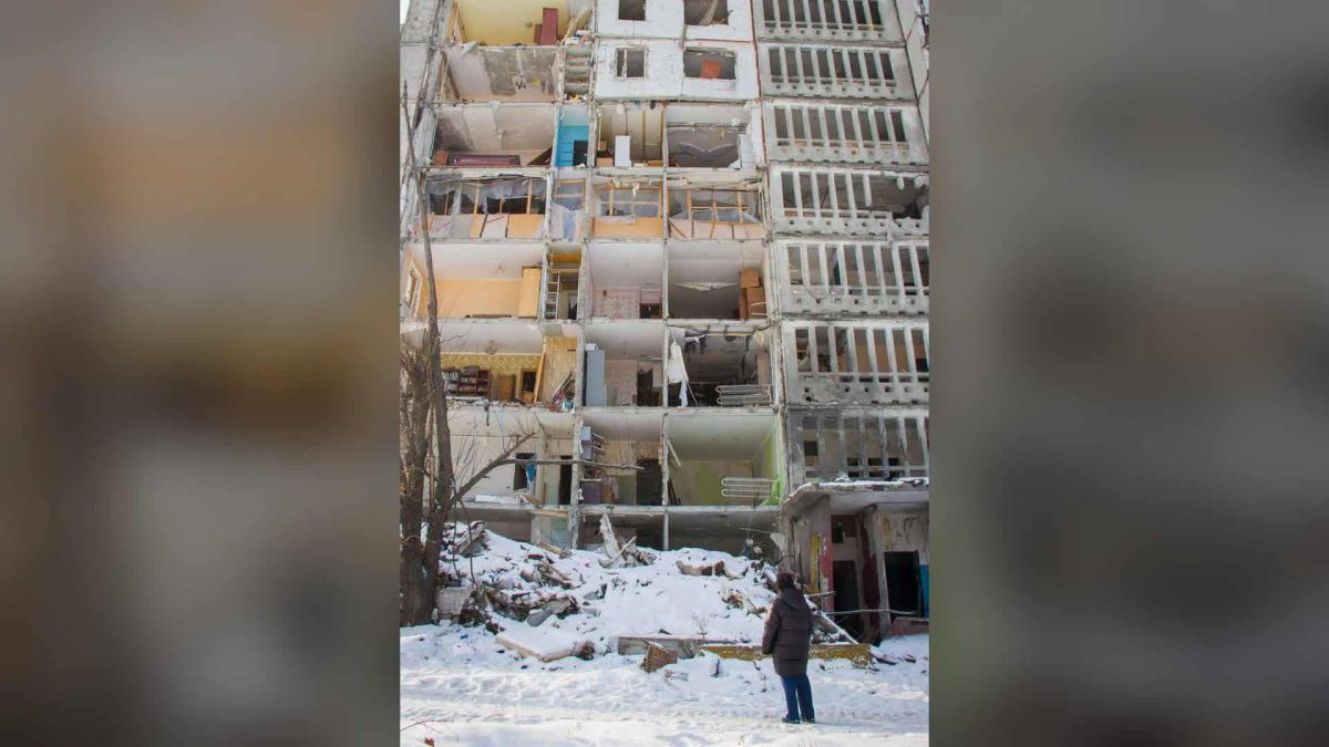 Бездомних у Києві вшестеро більше, ніж в офіційних даних Людина стоїть перед зруйнованим багатоповерховим будинком узимку — фото зі звіту про бездомність