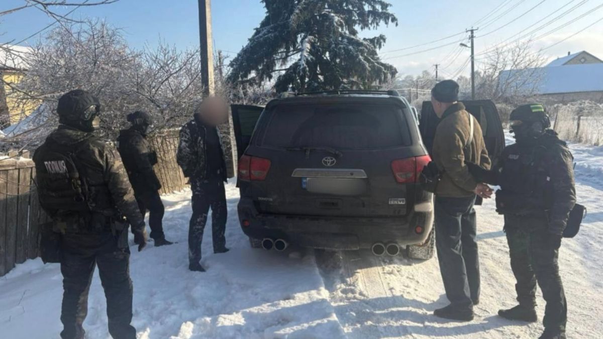 На Київщині затримали злочинну групу які вимагали у 47-річної фермерки $130 тисяч Силовики і затриманий підозрюваний біля чорного автомобіля