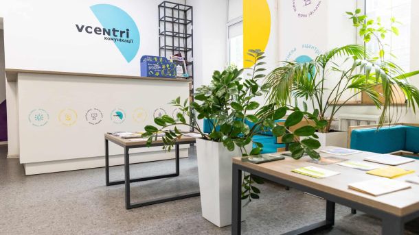 Інтер'єр громадського простору Vcentri HUB зі стійкою реєстрації, столами з інформаційними матеріалами та кімнатними рослинами