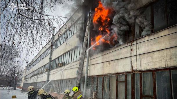 Рятувальники ДСНС у жовтих касках гасять масштабну пожежу в офісній будівлі у Білій Церкві, полум'я та густий чорний дим вириваються з верхнього поверху