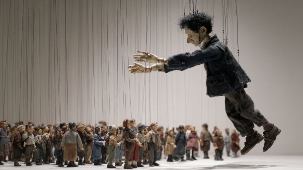 Великий маріонетковий персонаж на нитках контролює натовп маленьких фігур — метафора контролю ШІ-агентів над людьми