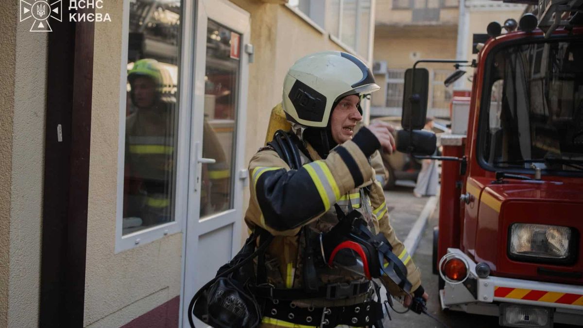 Уламки БпЛА впали на покрівлю житлового будинку у Солом’янському р-ні Рятувальник ДСНС у повному захисному спорядженні стоїть біля пожежного автомобіля на місці виклику вдень